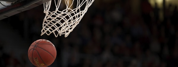 篮球运动员完成霸气扣篮后悬挂在篮筐上的瞬间